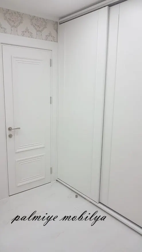 Damask duvar kağıdı altında beyaz panelli ahşap kapı ve yanında sürgülü dolap