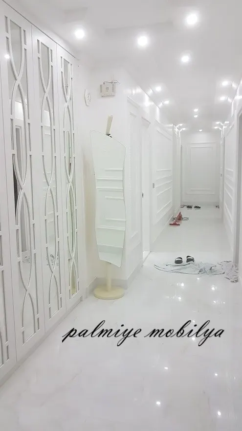 Beyaz koridorda kemer desenli aynalı gardırop kapakları ve lambrili duvarlar