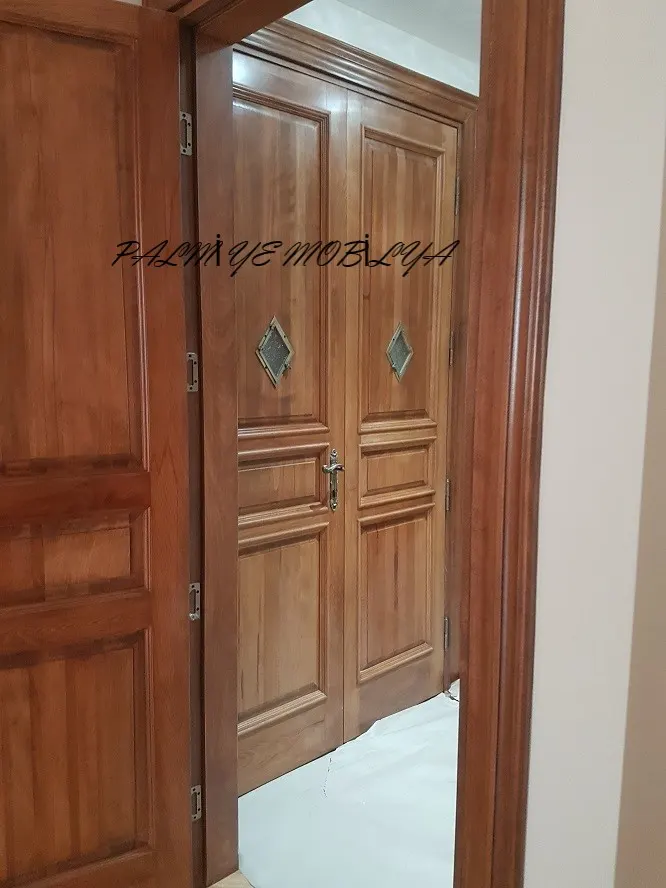 Açık kapı aralığından görünen baklava camlı ve pirinç kollu çift kanatlı ahşap kapı