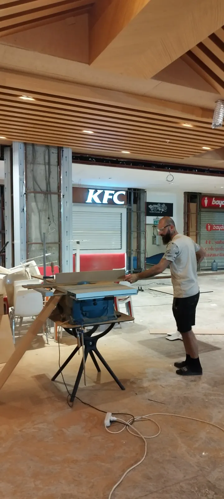 Mağaza iç dekorasyonu sırasında ahşap çıtalı tavan altında masa testeresiyle kesim