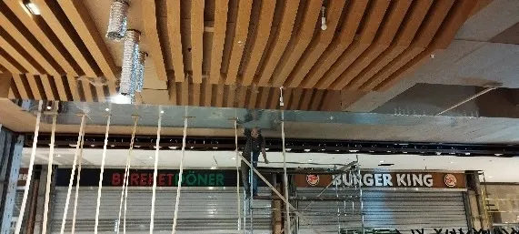 Kepenkleri kapalı dükkanların üzerinde hava kanalları görünen yarım kalmış ahşap çıtalı tavan