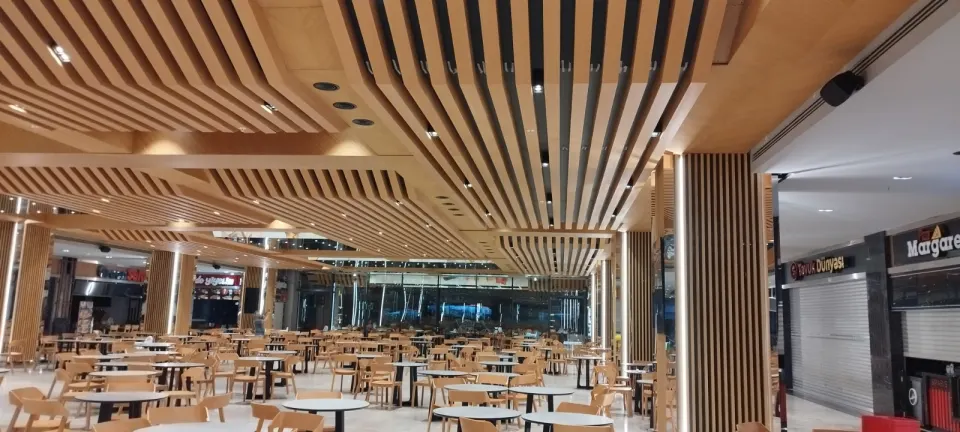 Yemek alanı boyunca uzanan ahşap çıtalı tavan ve kapalı dükkanların önündeki çıta kolon