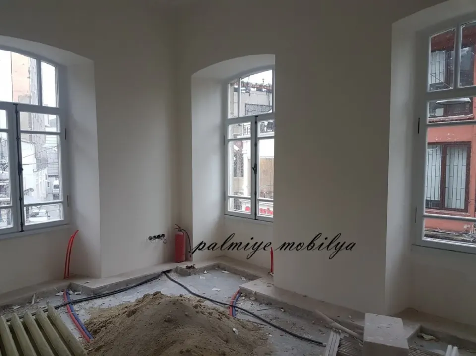 Tadilattaki tarihi binada kemerli pencereler, tesisat boruları ve kum yığını