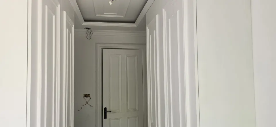 Villa koridorunda beyaz profilli duvar dolapları ve sonda dört panelli beyaz kapı