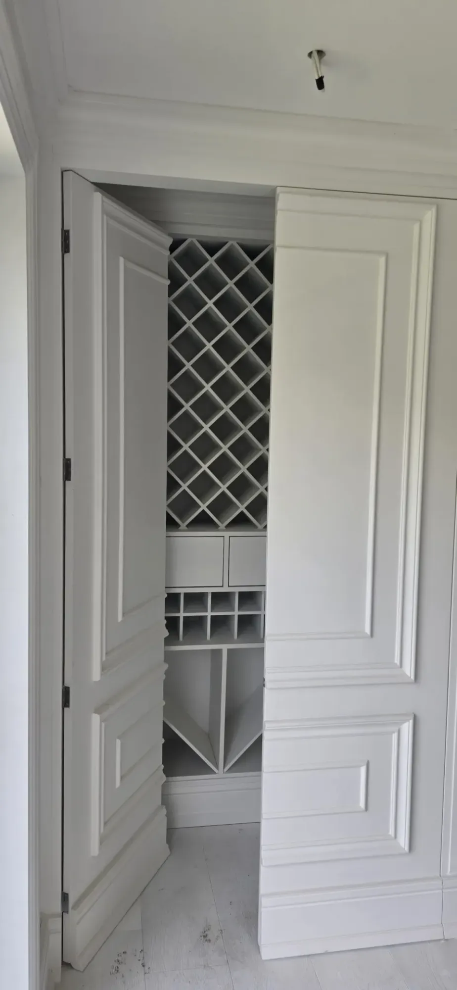 Beyaz panel kapakların ardında baklava gözlü şarap rafı bulunan villa dolabı