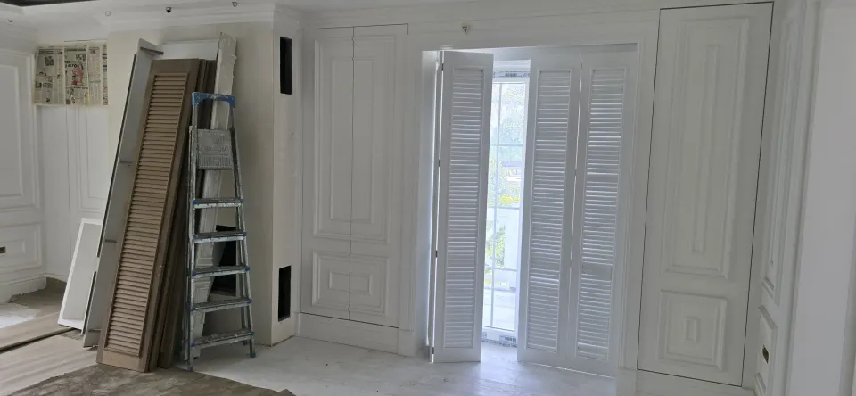 Villada panjur kanatlı beyaz balkon kapısı ve duvara dayalı ahşap panjurlar